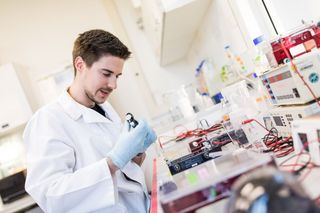 Ein männlicher Forscher führt ein biochemisches Experiment im Labor durch und arbeitet mit einer Pipette und Reagenzgläsern.