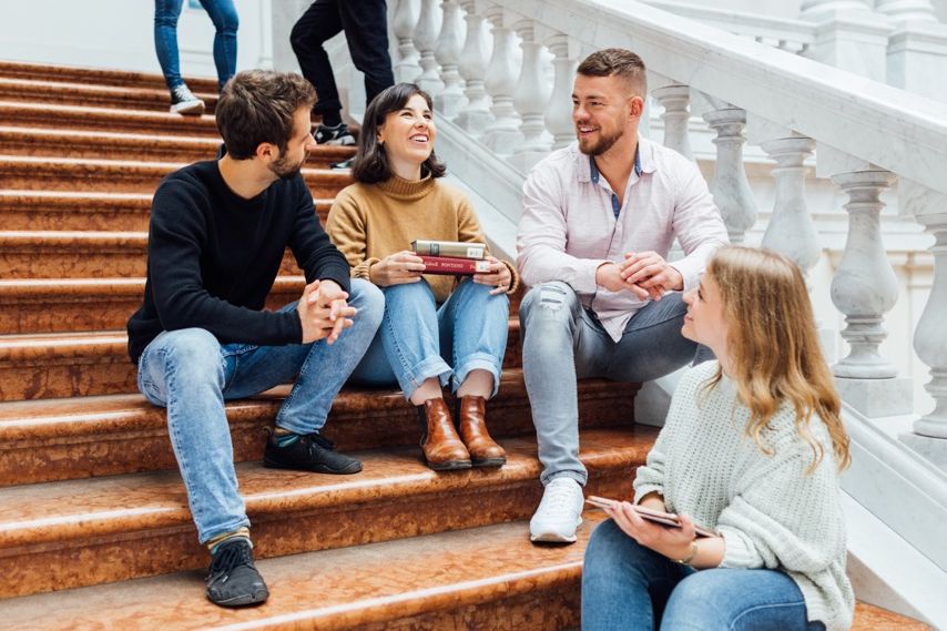 zur Vergrößerungsansicht des Bildes: Eine Gruppe Studierende im Gespräch auf der Treppe sitzend in der Bibliotheca Albertina der UNiversität Leipzig