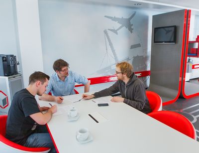 Foto: drei junge Männer sitzen an einem Tisch in einem modern eingerichteten Büro