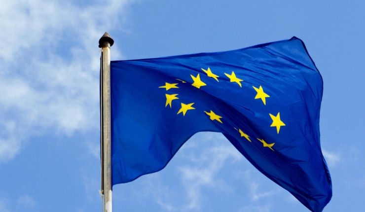Symbolbild: Die europäische Flagge weht im Wind, dahinter ist hellblauer Himmel.